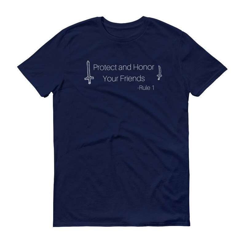 May include: Navy blue t-shirt with the text "Protect and Honor Your Friends - Rule 1" in white. The design includes line drawings of a sword and a dagger. The shirt is a short-sleeved crew neck.