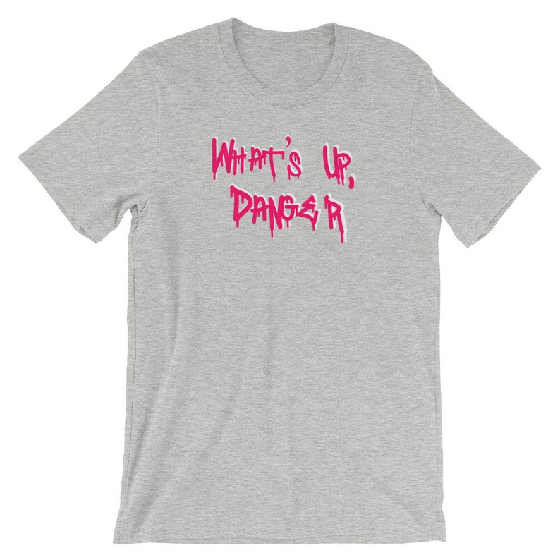 Puede incluir: Camiseta gris jaspeado con la frase "WHAT'S UP, DANGER" en letras rosas goteantes. Esta camiseta de manga corta est&aacute; hecha de un material suave, adecuada para el uso diario.