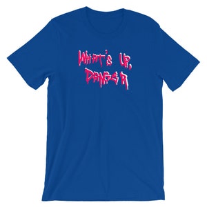 Puede incluir: Camiseta azul real con el texto "WHAT'S UP, DANGER" en una fuente roja y blanca que gotea. La camiseta es de cuello redondo y manga corta.