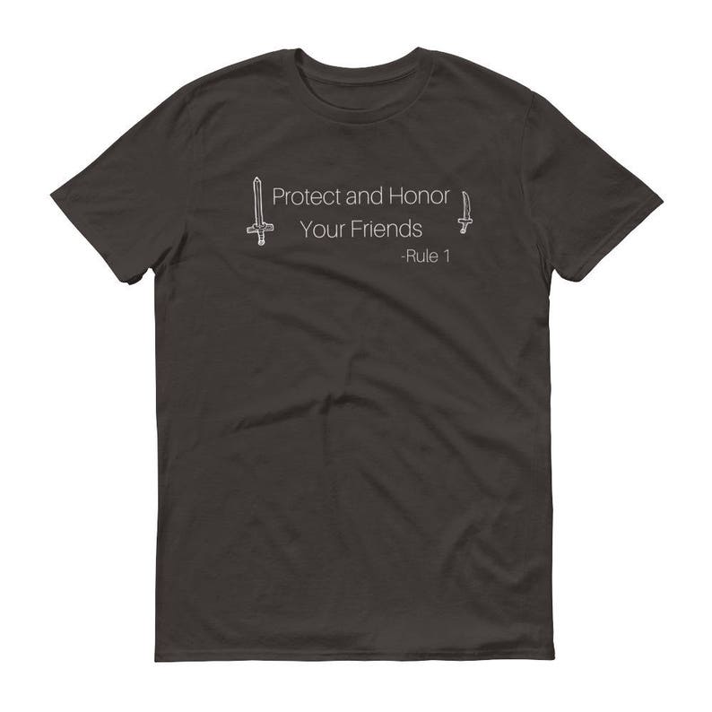 May include: Dark gray t-shirt with the text "Protect and Honor Your Friends - Rule 1" in white. The design includes stylized sword illustrations on either side of the text. A casual, everyday wear tee.