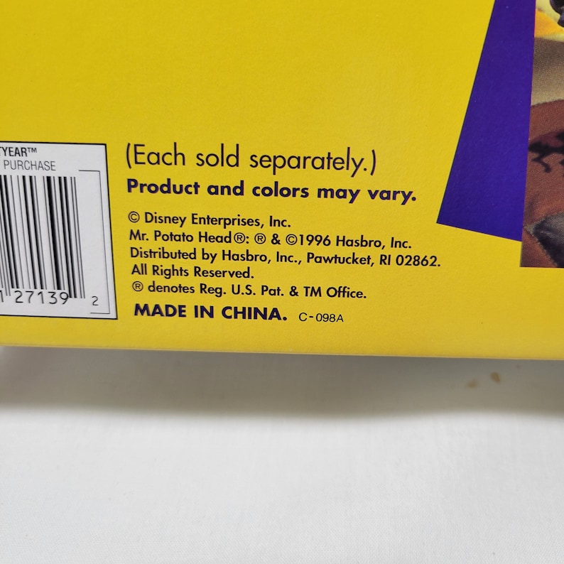 Peut inclure: Emballage de produit jaune et violet avec un code-barres et du texte qui lit "YEARTM PURCHASE", "(Vendu s&eacute;par&eacute;ment.)", "Produit et couleurs peuvent varier.", "&copy; Disney Enterprises, Inc.", "Mr. Potato Head&reg;: &reg; & &copy;1996 Hasbro, Inc.", "Distribu&eacute; par Hasbro, Inc., Pawtucket, RI 02862.", "Tous droits r&eacute;serv&eacute;s.", "&reg; d&eacute;signe Reg. U.S. Pat. & TM Office.", "FABRIQU&Eacute; EN CHINE. C-098A"