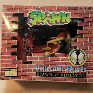 May include: A collectible action figure set featuring Spawn vs. Violator. The box has a brick wall design and the Spawn logo in green and purple. The set includes two figures, with the Violator figure having a large open mouth.