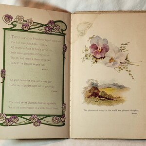 May include: Open book with text and illustrations. The left page has a poem with floral border. The right page features a floral illustration of purple and white pansies, and a landscape scene. The text reads, "The pleasantest things in the world are pleasant thoughts."