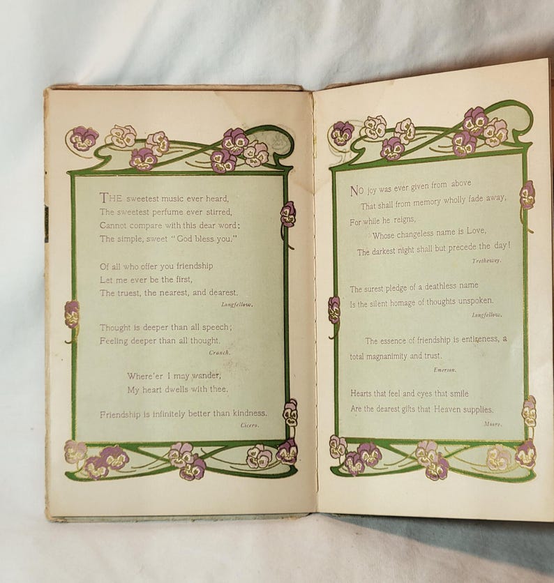 May include: Open book with two pages of poetry. Each page has a green border with floral designs in purple and white. The text is in a classic font, with poems about friendship and love.