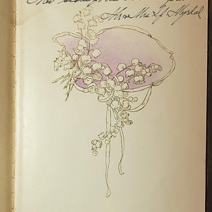 May include: An open book page with handwritten text and a floral illustration. The illustration features a hat shape in light purple with white flowers and ribbons. The text is in cursive.