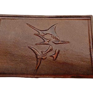 May include: A brown leather patch with two marlin fish silhouettes embossed in the centre.