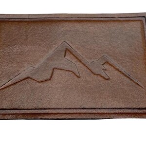 Peut inclure: Un patch en cuir marron avec un motif en relief d'une chaîne de montagnes.