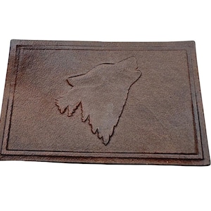 May include: A brown leather doormat with a raised design of a wolf howling at the moon.