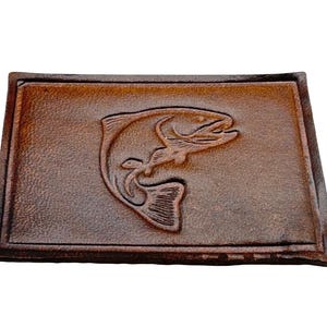 Könnte beinhalten: Ein braunes Lederstück mit einem detailliert geprägten Bild eines springenden Fisches.