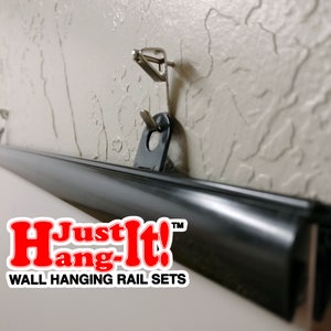 May include: A black wall hanging rail set with the text "Just Hang-It!" in red letters. The rail is mounted to a wall with two silver hooks.