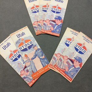 May include: Five vintage travel maps from the Utah Oil Refining Company. The maps are for Idaho, Utah, and Idaho-Montana-Wyoming. Each map features a blue and red UTOCO logo with a torch and the text "Let's Go with UTOCO".