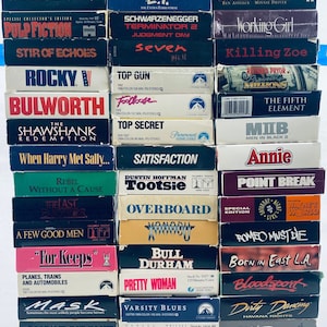 May include: A stack of VHS tapes featuring popular movies from the 1990s and early 2000s, including Pulp Fiction, Terminator 2, Seven, Top Gun, The Shawshank Redemption, When Harry Met Sally, Tootsie, Pretty Woman, and more.