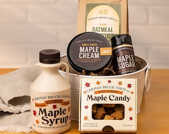 May include: A white metal bucket filled with maple syrup, maple cream, maple sugar, and maple candy. The products are all from Carman Brook Farm in Vermont.