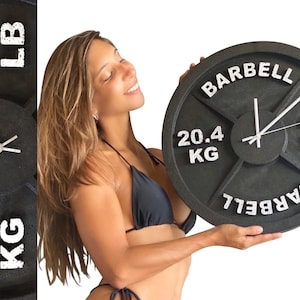 May include: A black weight plate clock with white lettering that reads "BARBELL" and "20.4 KG" and "45 LB".