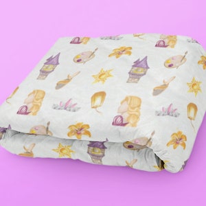 Peut inclure: Une couverture blanche pliée avec un motif répété d'une tour violette, d'un soleil jaune, d'une fleur jaune, d'une lanterne jaune et d'une femme blonde avec une robe violette.