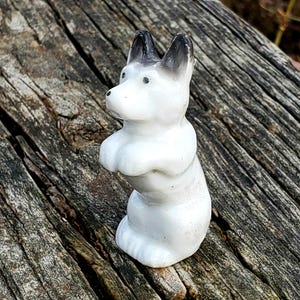 Miniatuur zwart-wit porseleinen hondje uit de jaren 40 met smekende gezichtsuitdrukking