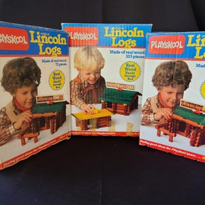 May include: Three vintage Playskool Lincoln Logs boxes with colorful illustrations of children playing with the wooden building blocks. The boxes feature the text "Playskool Lincoln Logs" and state that the logs are made of real wood. The boxes are in good condition and show signs of age.