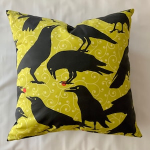 May include: A green throw pillow with a black crow pattern and red berries. The crows are silhouetted against a green background with a swirling pattern.