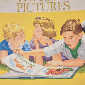 May include: Vintage children's book cover with the text "WE READ PICTURES" in gold lettering. The illustration shows three children looking at an open book with colorful drawings. The background is yellow and the book is on a blue surface.