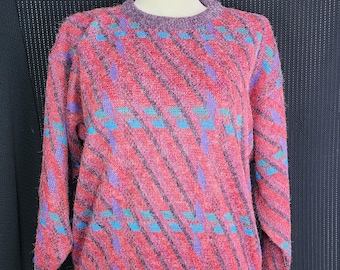 May include: A vintage sweater with a vibrant pattern. The sweater features a red base with diagonal stripes in black, accented by blue and purple geometric shapes. The collar, cuffs, and hem are a solid purple color. The sweater is displayed on a mannequin.