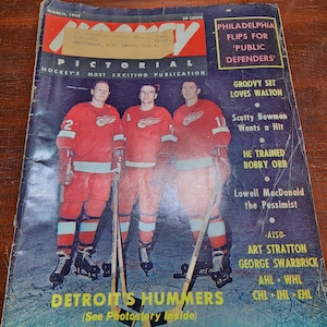 以下が含まれることがあります： 赤い白のユニフォームを着た3人のホッケー選手が、ホッケーのスティックを持っている、ビンテージ雑誌の表紙。雑誌のタイトルは「Hockey Pictorial」で、表紙のテキストは「Detroit's Hummers (See Photostory Inside)」です。