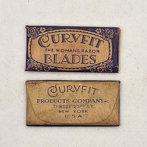 May include: Two vintage boxes of Curvfit razor blades. The top box is blue with gold lettering and floral designs. The bottom box is brown with black lettering and a curved design. The text on the boxes reads "Curvfit The Woman's Razor Blades" and "Curvfit Products Company Inc. 71 West 23rd St. New York U.S.A."