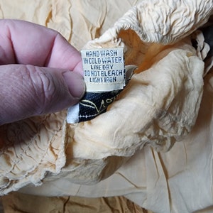 May include: A close-up of a yellow fabric care label with the text "Hand wash in cold water, line dry, do not bleach, light iron".