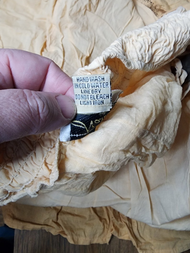 May include: A close-up of a yellow fabric care label with the text "Hand wash in cold water, line dry, do not bleach, light iron".