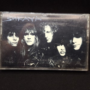 May include: A black and white cassette tape with the band name "SARAYA" printed on the front. The band members are pictured on the front of the cassette tape.