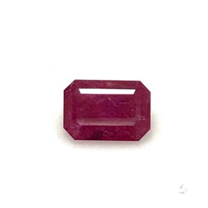 May include: A deep red emerald cut gemstone.