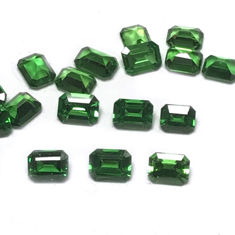 May include: A collection of emerald green gemstones cut in a rectangular emerald shape.