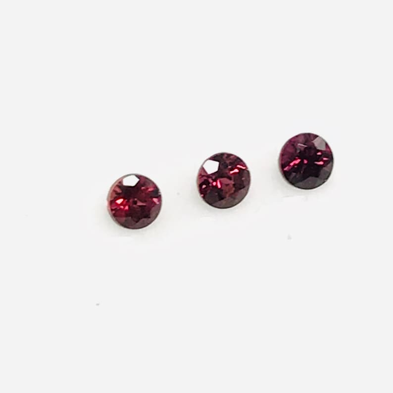 May include: Three round, faceted, dark red gemstones.