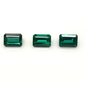 May include: Three emerald green gemstones cut in a rectangular emerald shape.