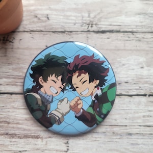May include: A round button featuring two anime characters, one with green hair and the other with red hair, smiling and bumping fists. The background is a blue and white pattern.