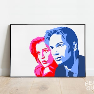 May include: A pop art style print of two figures in blue and pink, set against a white backdrop. The artwork is framed in black and includes the text "BEAU OUI?" in the lower right corner. The image is displayed on a light wood floor.