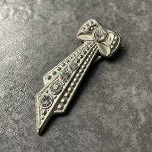 Vintage Art Deco style single dress clip. Silver tone ribbon design set with clear paste stones.