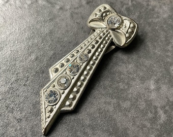 Vintage Art Deco style single dress clip. Silver tone ribbon design set with clear paste stones.