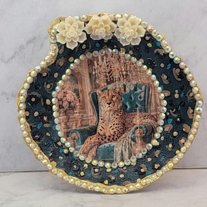 Schmuckschale aus der Cheetah-Kollektion in Muschelform, mit perlmuttfarbenen oder akzentuierten Füßen, in Gold-, samtig-bläulich-grünen oder küstenblauen Farbtönen.