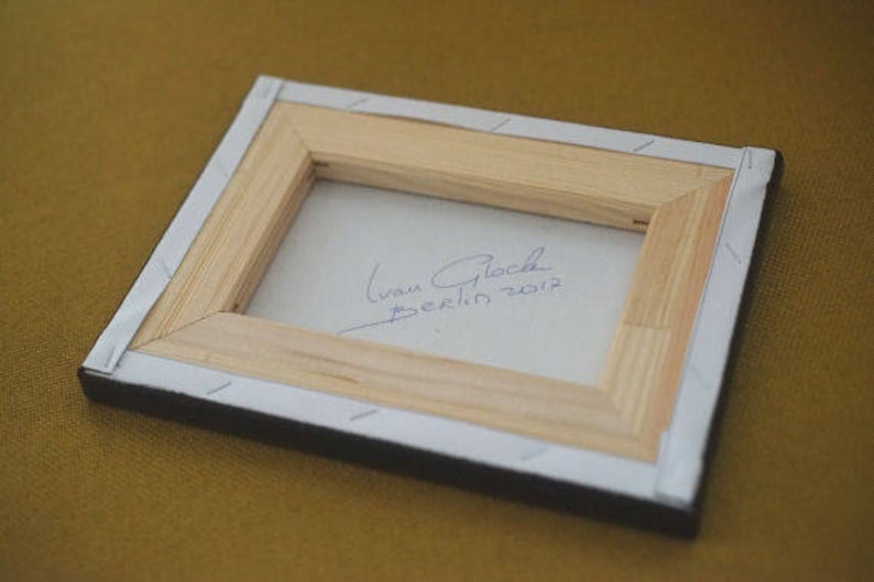 May include: A wooden frame with a white background and a handwritten signature that reads "Ivan Glock Berlin 2012".