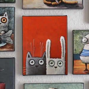 May include: A painting of a gray cat and a white rabbit with big eyes, looking at the viewer. The animals are on a red background.