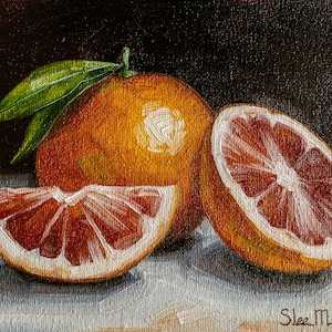 Op de afbeelding: Een stilleven schilderij met drie bloedsinaasappelen, één geheel en twee gehalveerd, op een wit oppervlak. De sinaasappelen zijn in een levendige oranje en rode kleur, met een donkerbruine achtergrond.
