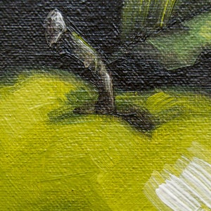 May include: Close-up of a green apple with a brown stem. The apple is painted with thick strokes of green paint, giving it a textured appearance.