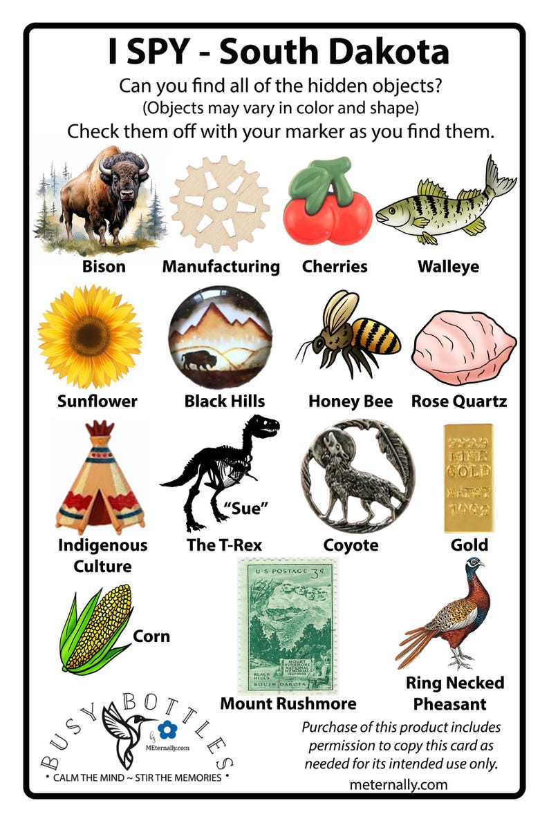 Peut inclure: Une carte de jeu I Spy South Dakota illustrant un bison, un engrenage, des cerises, un dor&eacute; jaune, un tournesol, les Black Hills, une abeille, du quartz rose, un tipi, un squelette de T-Rex, un coyote, un lingot d'or, du ma&iuml;s, un timbre.