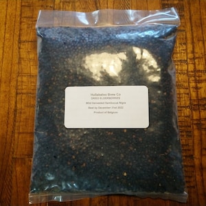 May include: A clear plastic bag filled with dried elderberries. The bag has a white label that reads "Hull's Habitation Farms Co. Dried Elderberries Wild Harvested Sambusca Nigra  Best by December 27th 2023 Product of Belgium"
