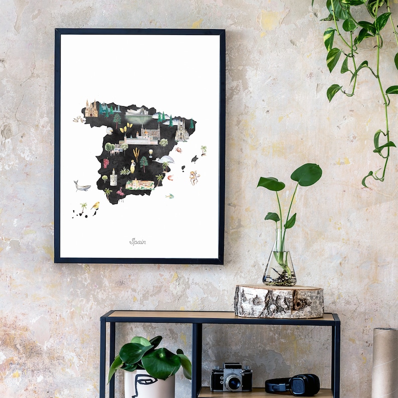 Puede incluir: Una impresi&oacute;n enmarcada en negro de un mapa de Espa&ntilde;a con ilustraciones de monumentos y animales. El mapa est&aacute; sobre un fondo blanco y la palabra "Espa&ntilde;a" est&aacute; escrita en negro en la parte inferior del mapa.