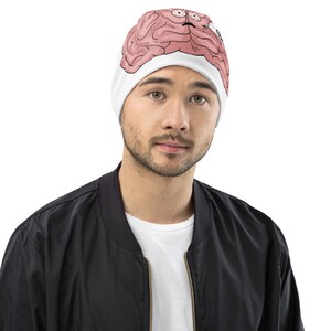 Puede incluir: Un gorro blanco con un gráfico de cerebro rosa y el texto "Oh no" impreso en el lateral.