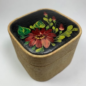 May include: A square wooden box with a black painted lid featuring a hand-painted floral design. The design includes a large red flower with yellow center and green leaves.