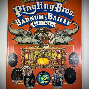 Peut inclure: Couverture du programme souvenir du cirque Ringling Bros. et Barnum & Bailey. La couverture est orange avec le nom du cirque en bleu et blanc. Un tigre et deux éléphants sont représentés. The Greatest Show on Earth est également imprimé.