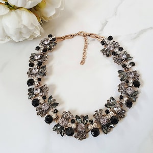 May include: A statement necklace with a gold chain and black and gray crystal embellishments.