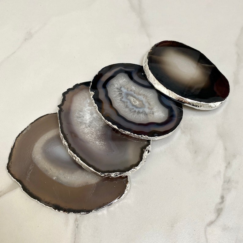 Peut inclure: Ensemble de quatre sous-verres en agate avec bordure argent&eacute;e. Les sous-verres sont ronds et ont un aspect naturel et organique. Ils sont parfaits pour prot&eacute;ger les surfaces des rayures et des d&eacute;versements.